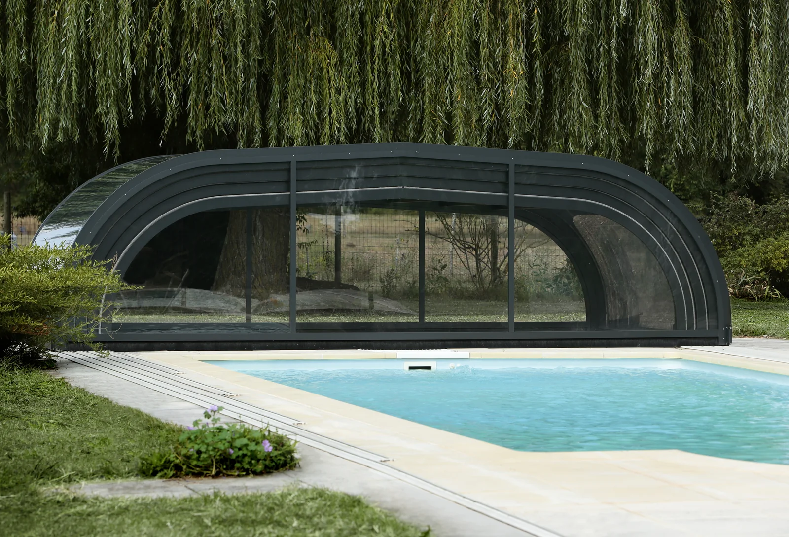 Abri de piscine bas cintré vu depuis le bord du bassin