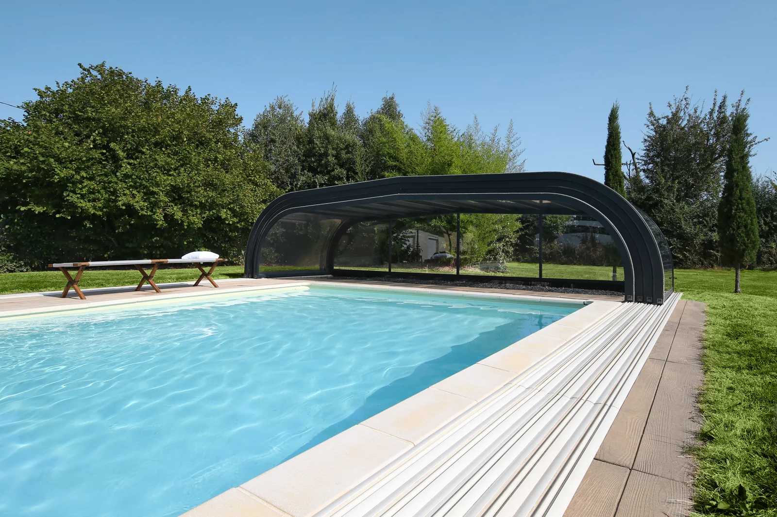 Abri de piscine bas cintré fermé au bord d’un bassin