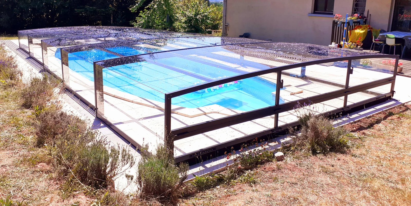 Abri de piscine bas coulissant installé autour d’un petit bassin