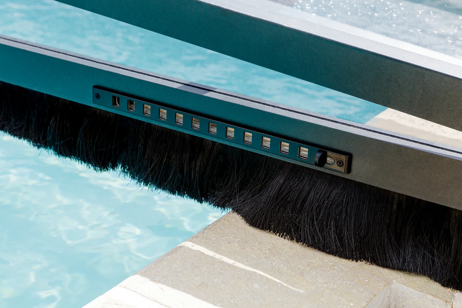 Détail de la brosse d’étanchéité au bas d’un abri de piscine