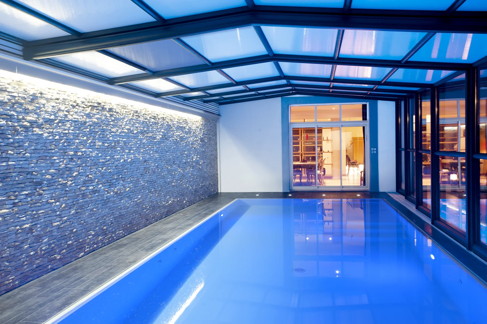 Vue intérieure d’un abri de piscine haut avec bassin éclairé