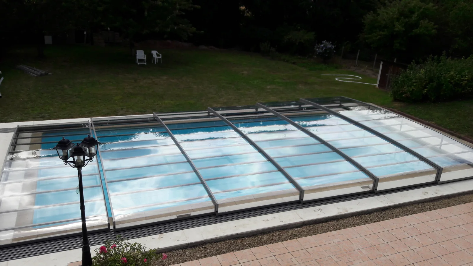 Abri de piscine plat installé parallèlement à une terrasse