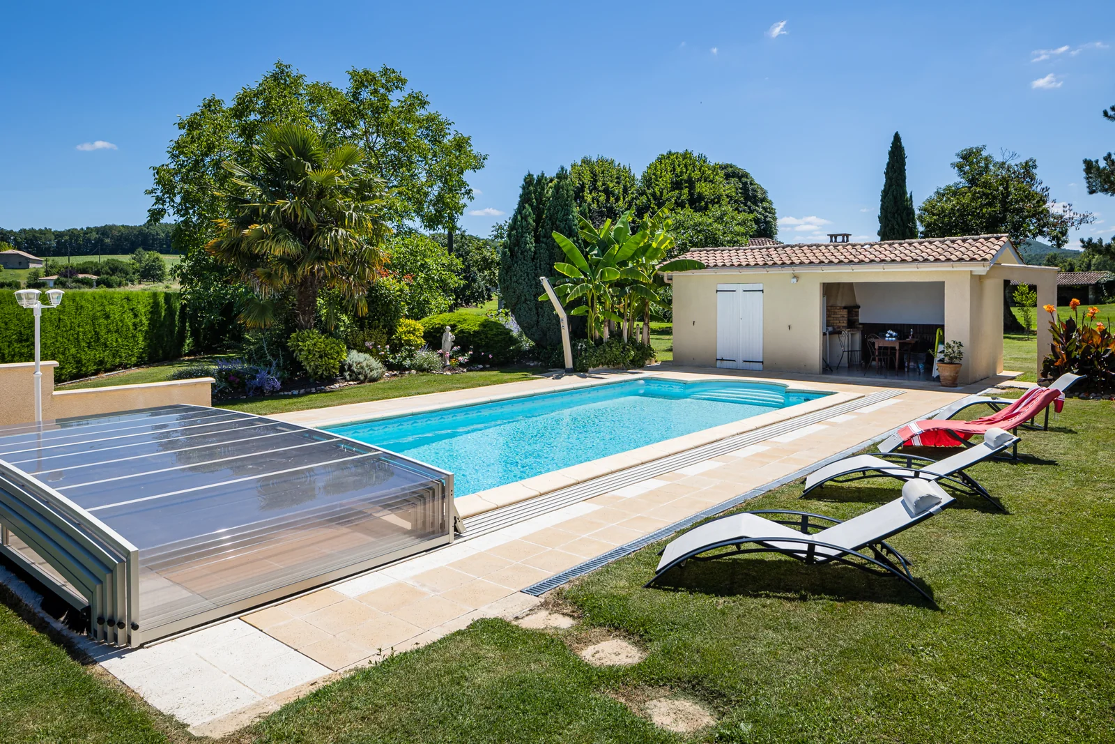 Abri de piscine semi-plat blanc partiellement ouvert dans un jardin
