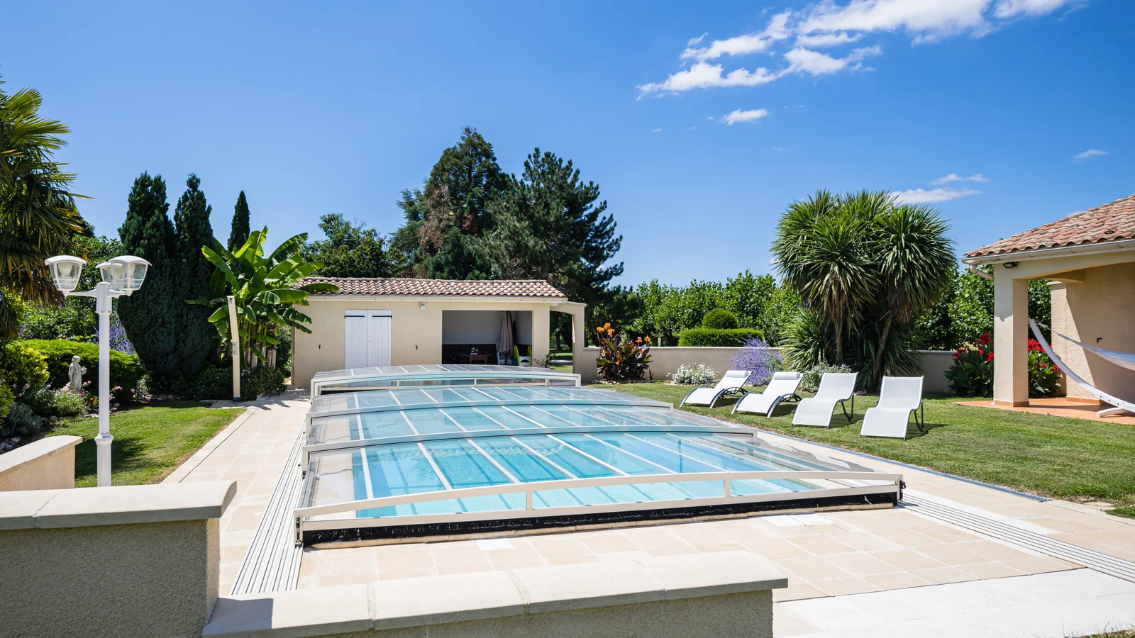 Abri de piscine semi-plat blanc fermé devant une maison