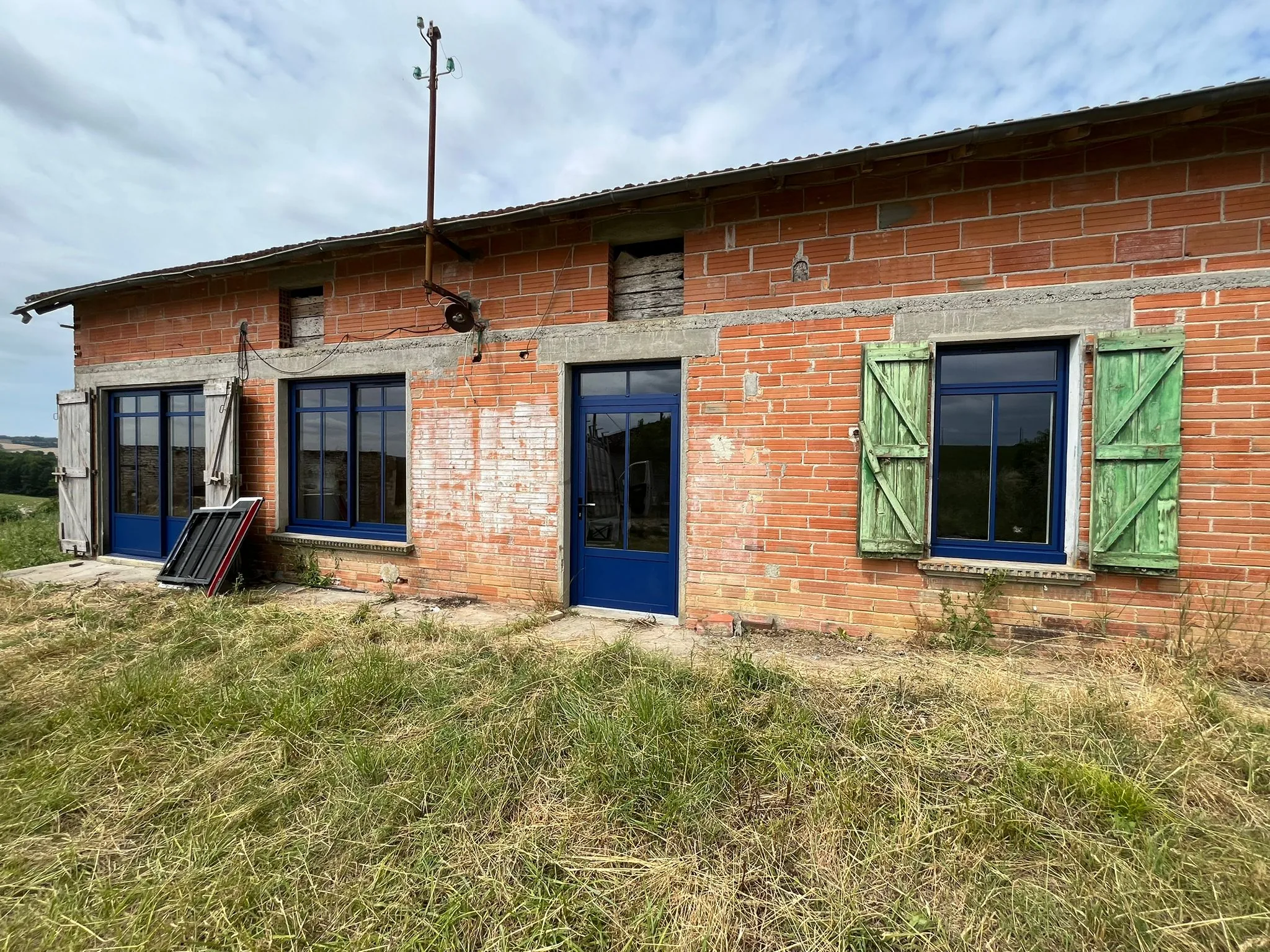 Façade en brique avec menuiseries aluminium bleues à Puycelsi