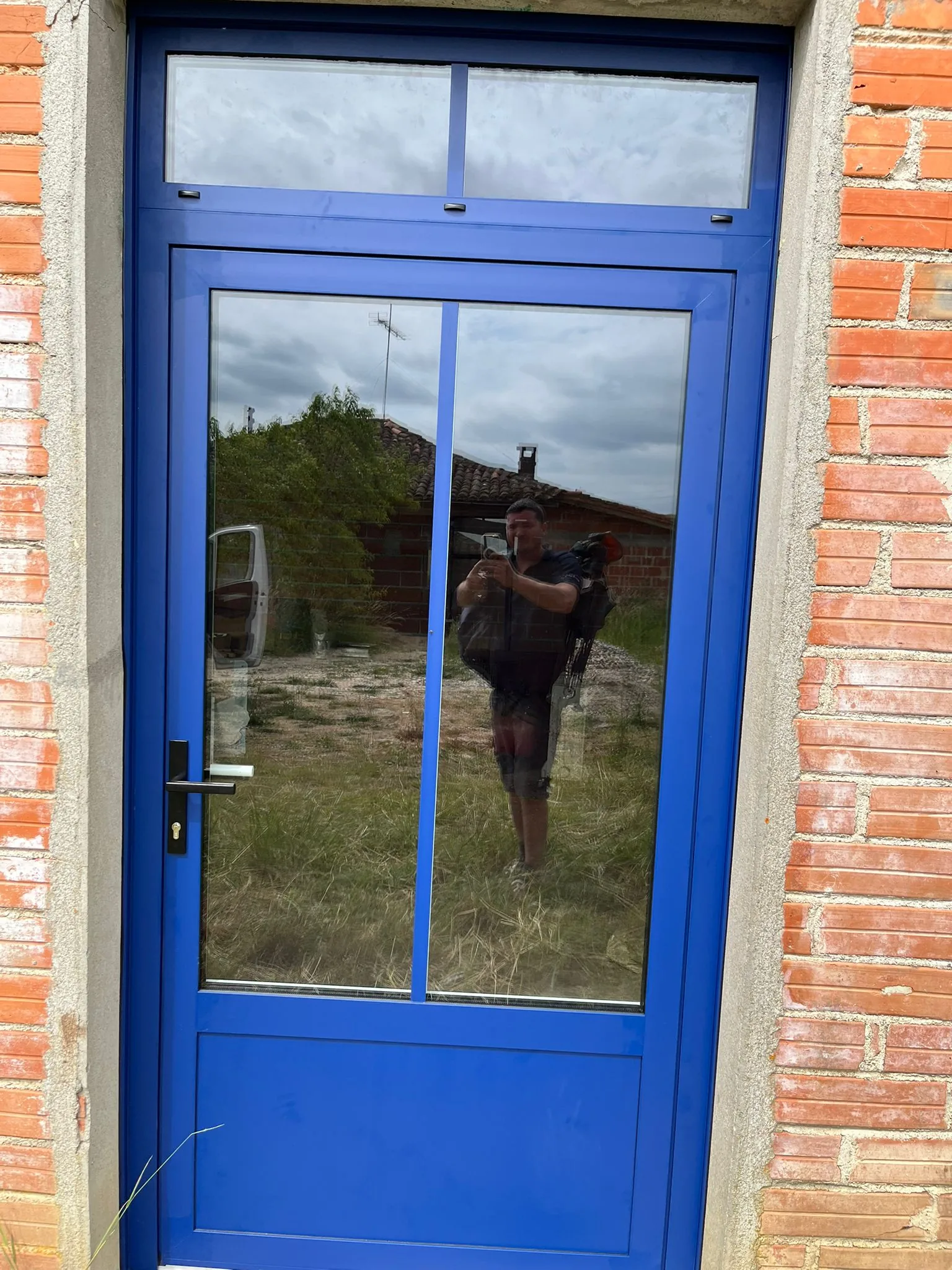 Porte vitrée aluminium bleue sur chantier à Puycelsi